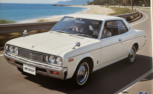 1970年代の自動車カタログ風の画像で、海岸線を走る白い4代目グロリア230型。ピラーレスハードトップの開放感が強調され、当時のスタイリッシュなデザインを伝える。