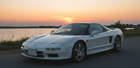 ホンダNSXが夕暮れの美しい空の下、湖畔の道に佇んでいる。夕陽に照らされた車体が、伝説的な存在感を放ち、読者の興味を引きつける。